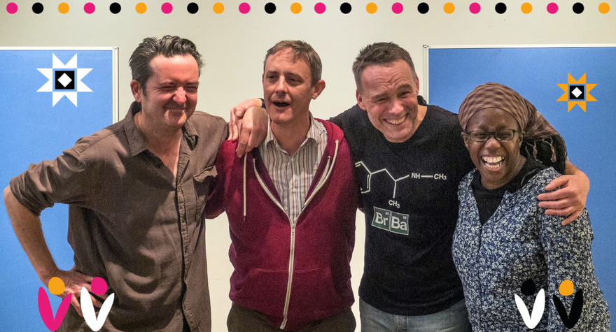 A group of four people huddled together with their arms around each other laughing