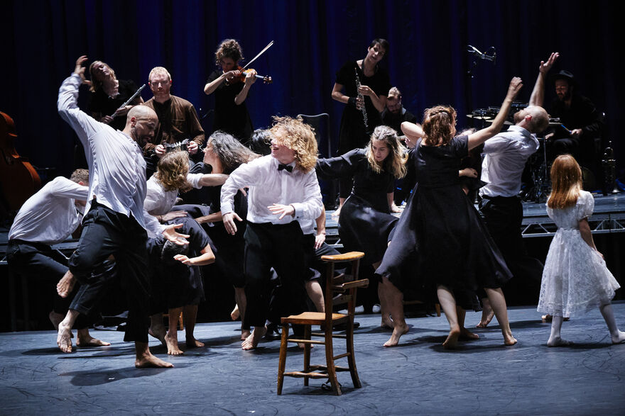 People of all ages dancing on a stage in white and black outfits