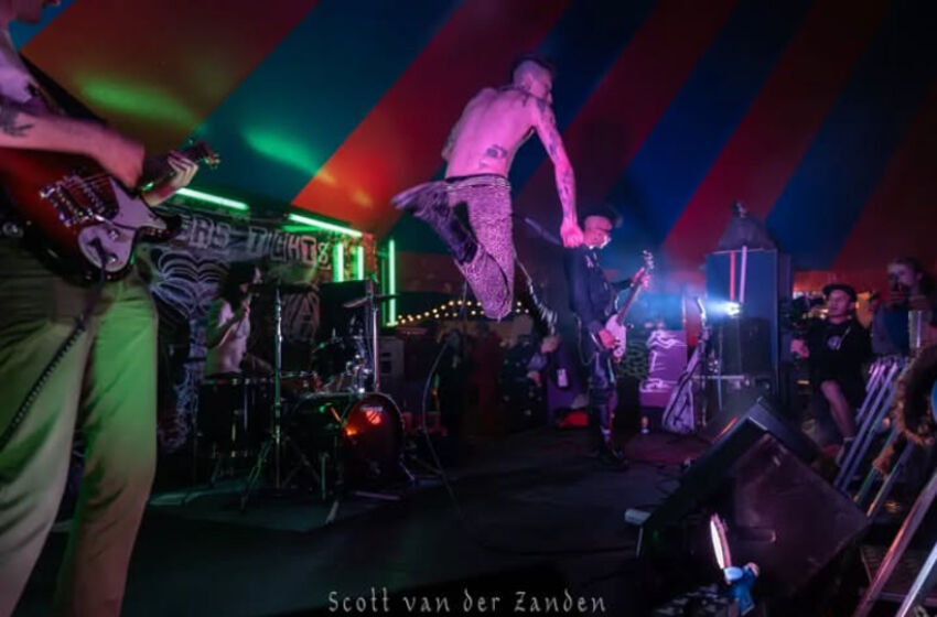 Electric Cowboy Club performing on stage, the lead singer jumps high