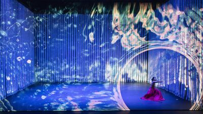 Two dancers twirling in floaty costumes, with glittering light projections around them