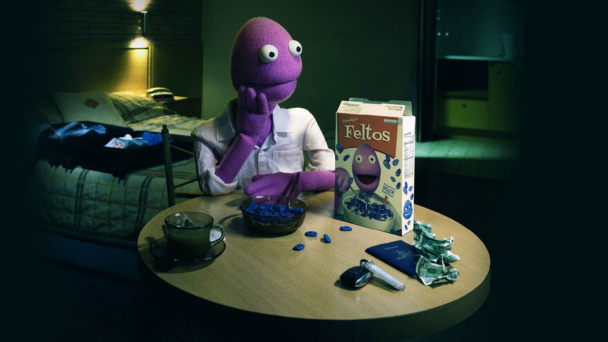 A purple fuzzy puppet sitting at a table in a dark room, their hand is on their face and there is a cereal box, money and a gun on the table.