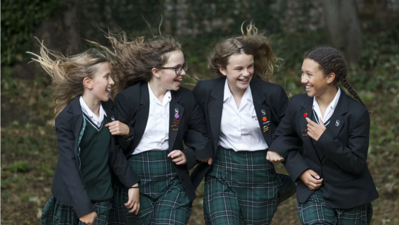 4 girls in school uniform linking arms and smiling