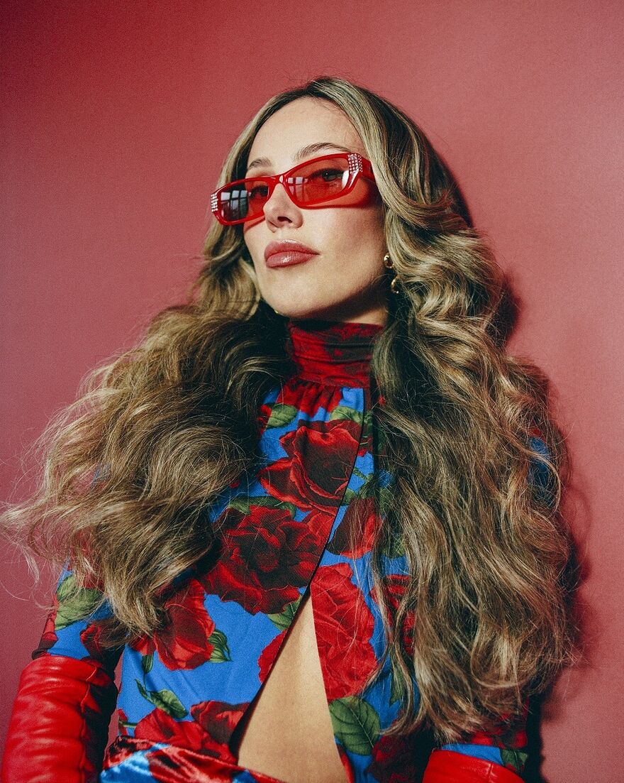 A woman with long brown/blonde hair wearing red sunglasses 