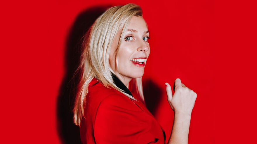 Sara Pascoe smiling against a red background