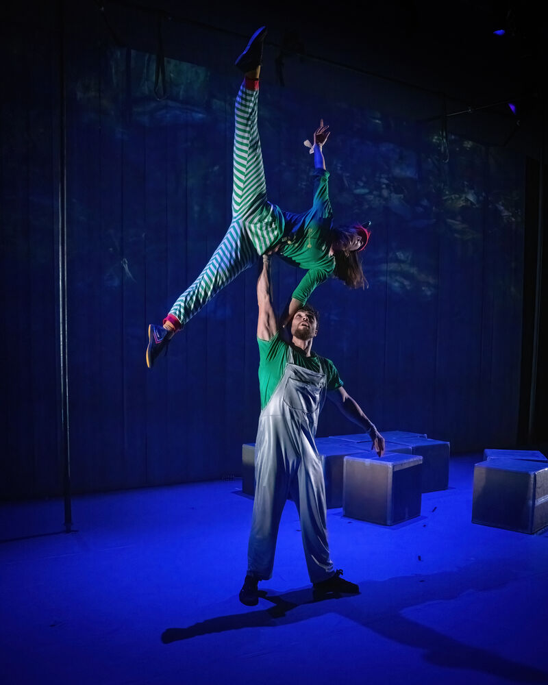 One performer is being lifted up by the other in an acrobatic pose