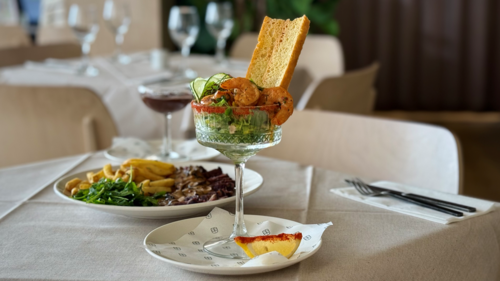 A table with a plate of steak and chips and a prawn cocktail on it