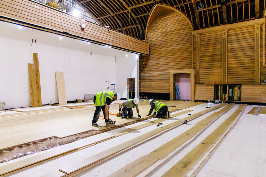Three builders working on installing flooring