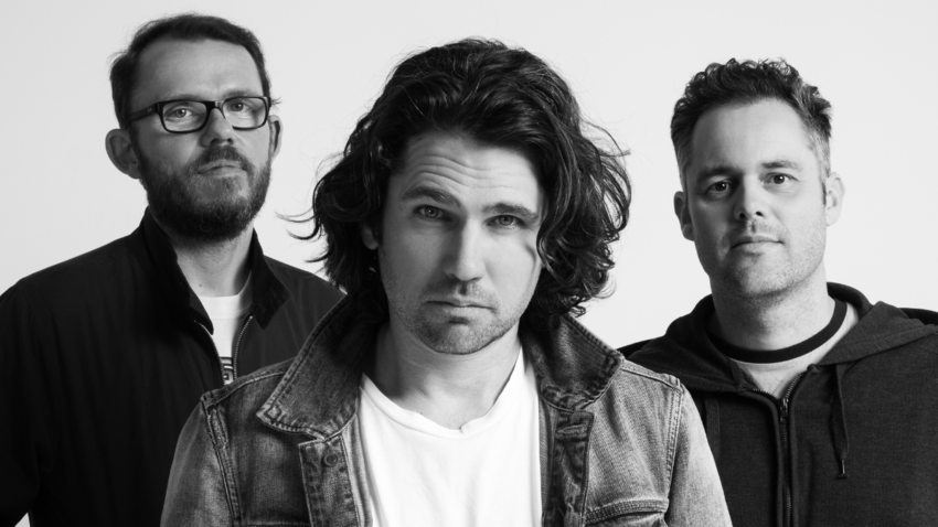 three men in a black and white picture stare into a camera