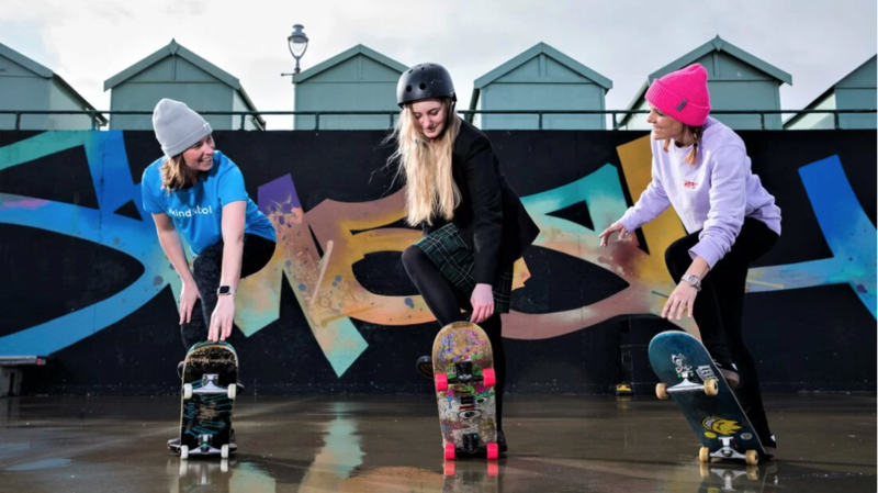 Three girls in a row learning how to skateboard