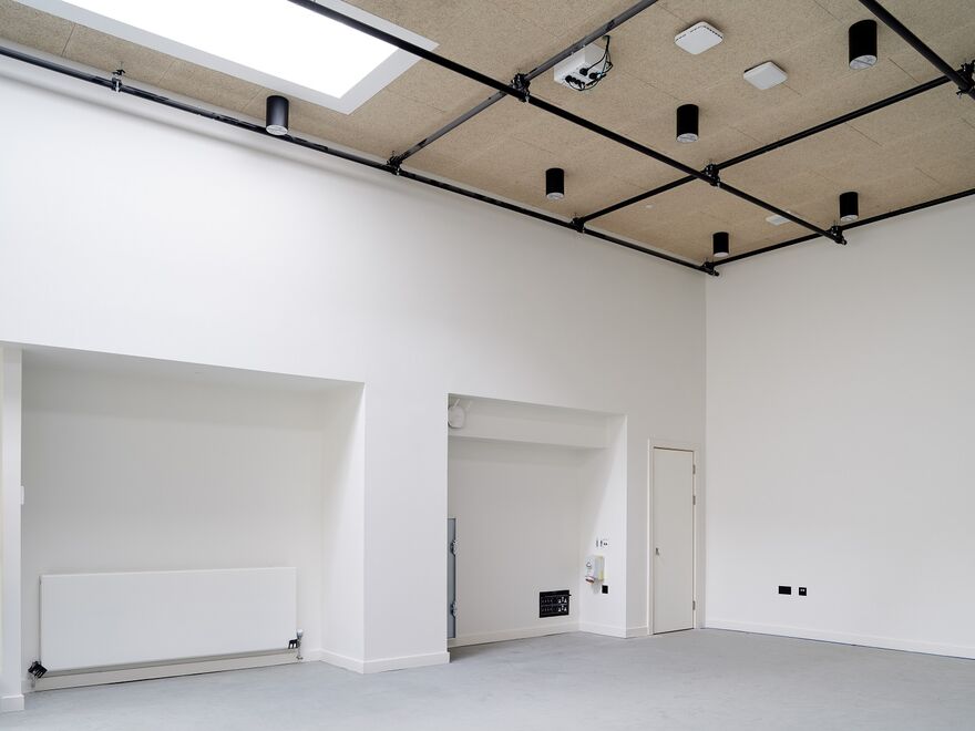 A white walled room with beige ceiling that has a black lighting rig on it