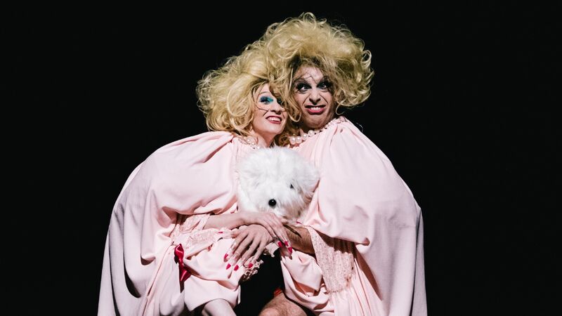 Two people in drag are holding a stuffed teddy bear