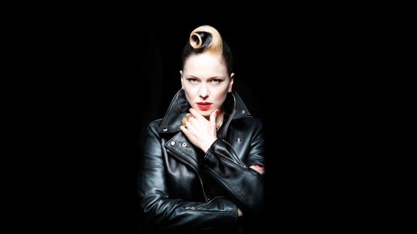 Imelda May singing on stage, with lights behind her