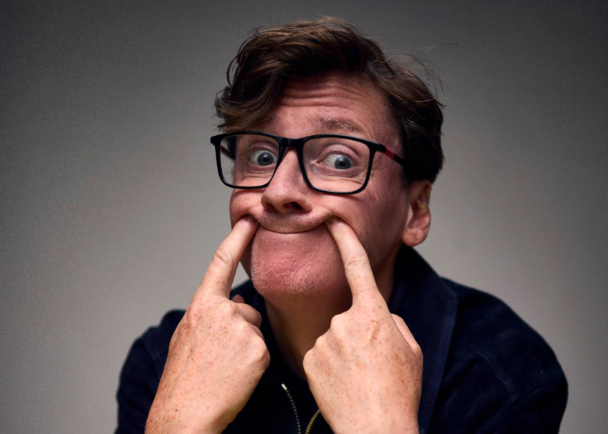 Ed Byrne putting his fingers in his mouth to make a smiley face