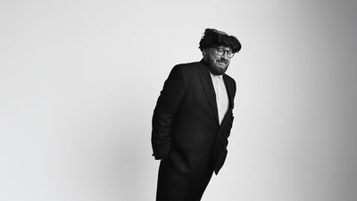 John Kearns wearing a black suit leaning to one side