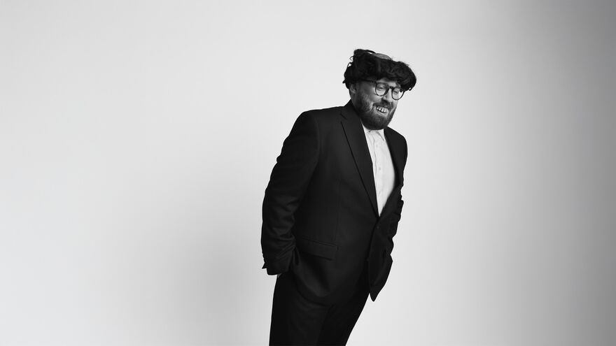 John Kearns wearing a black suit leaning to one side