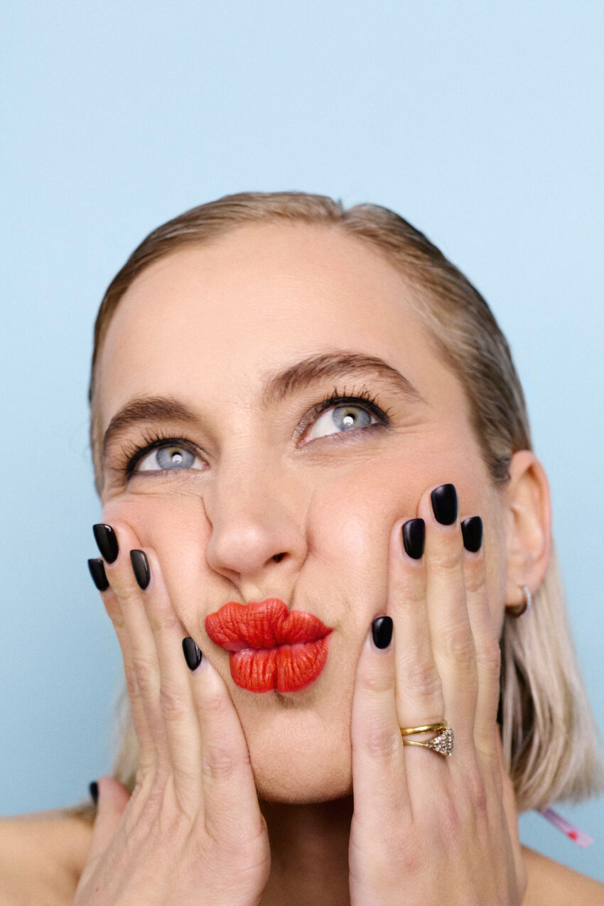 Lily Phillips pouting with red lipstick and black fingernails