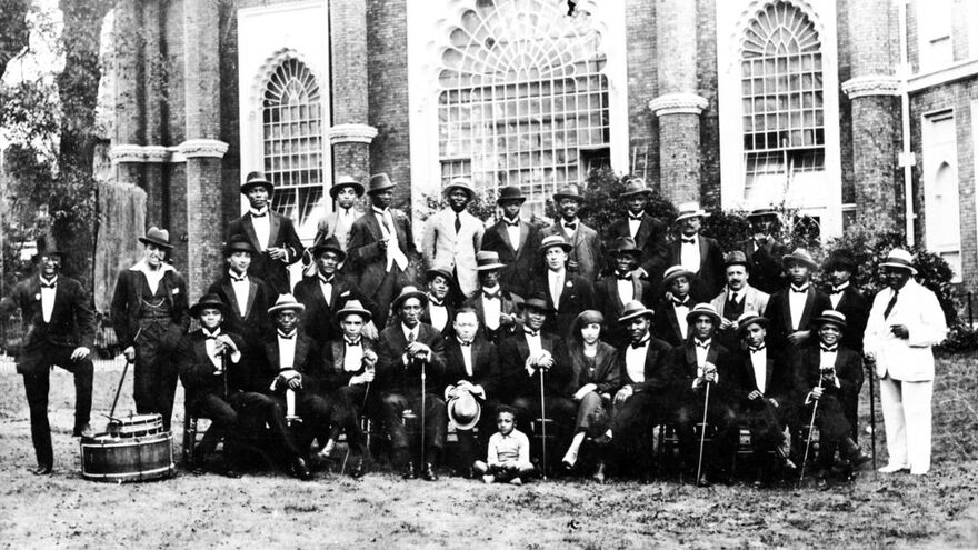 A large group of men wearing suits. They are standing in front of Brighton Dome. The picture is in black and white