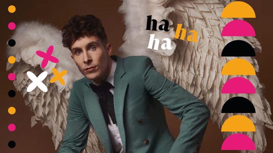 Larry Dean wearing a turquoise blazer, white shirt and black tie with angel wings made of feathers