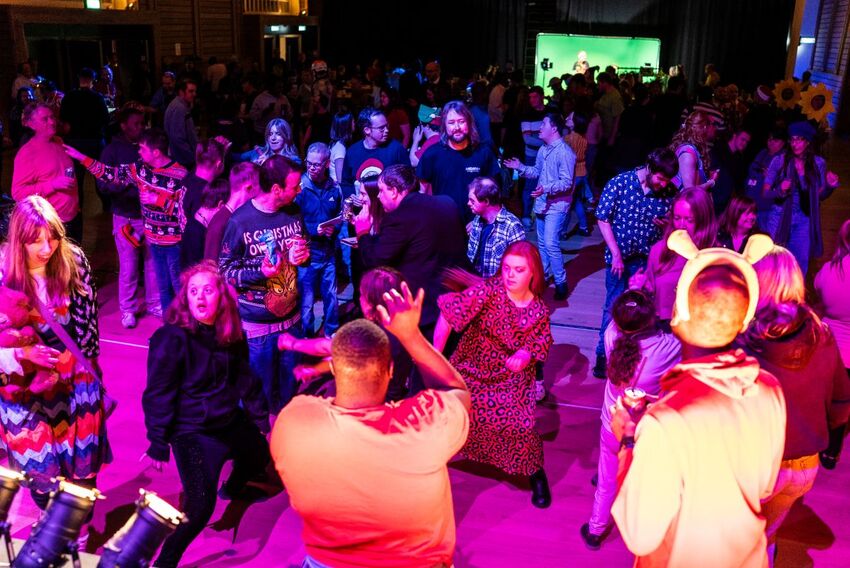 Group of people dancing in a room with purple lights