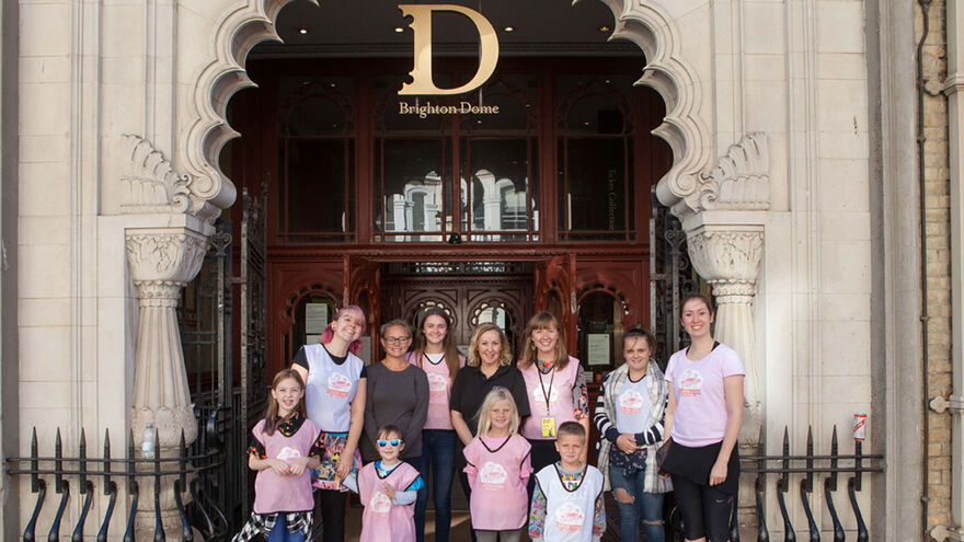 Members of Umbrella Club stand infront of Brighton Dome's gate with staff from Flamingo Chicks and Brighton Dome