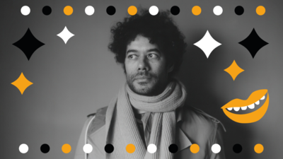 Black and white image of Richard Ayoade wearing a coat and scarf staring at the side