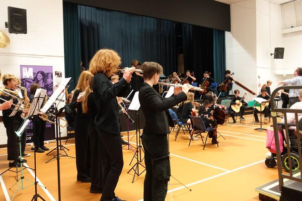 Youth orchestra performing in a school theatre
