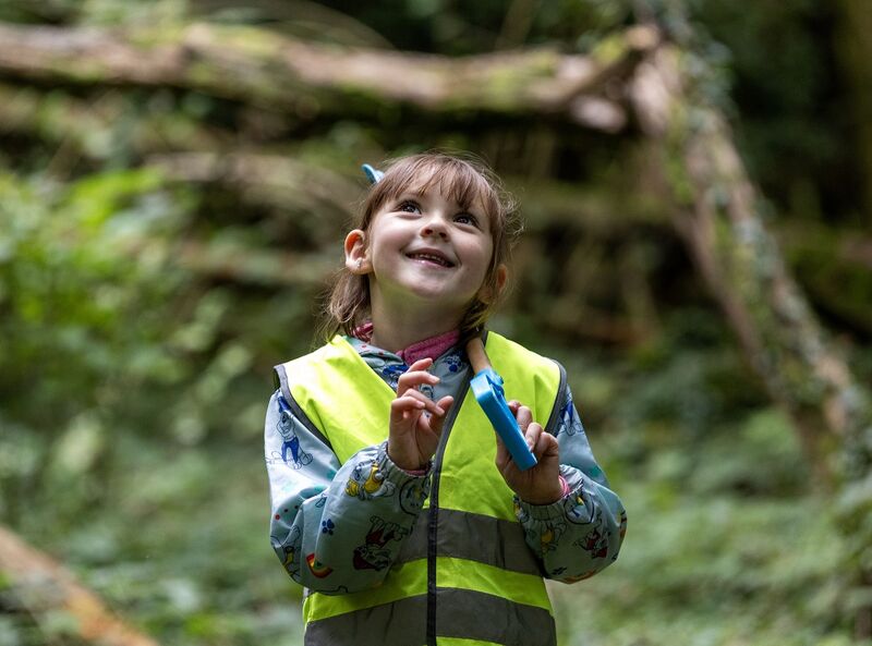 A young girl wearing a high vis in nature