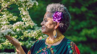 Akila Richards looking a white tree blossoms and gently cupping them with her hand