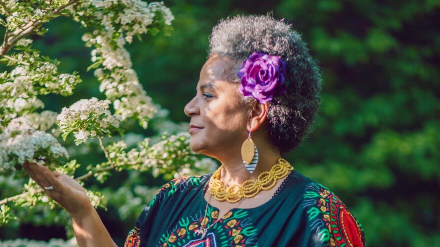 Akila Richards looking a white tree blossoms and gently cupping them with her hand