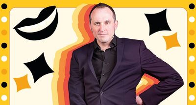 Phil Ellis wearing a dark suit standing surrounded by black and yellow stars and dots