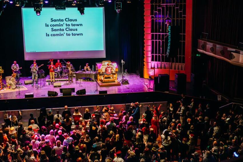 Band on stage with red and green lines and a standing audience