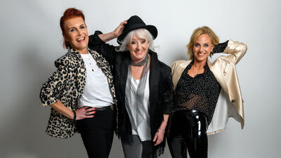 Three members of Fascinating Aida wearing neutral black, white, gold and silver tones