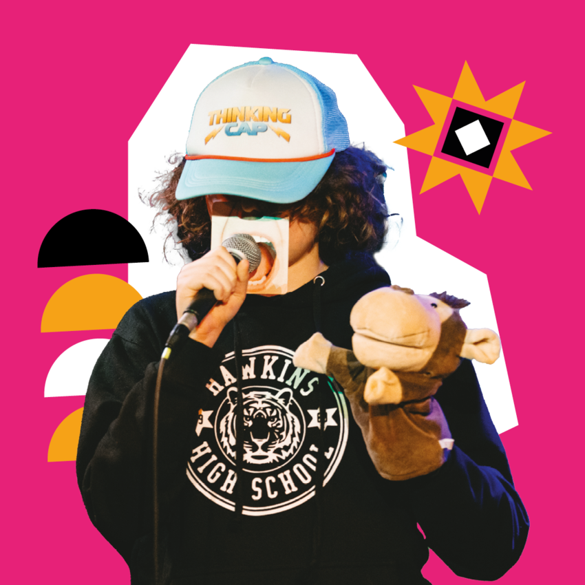 A performer wearing a 'thinking cap' holding a microphone and a money hand puppet