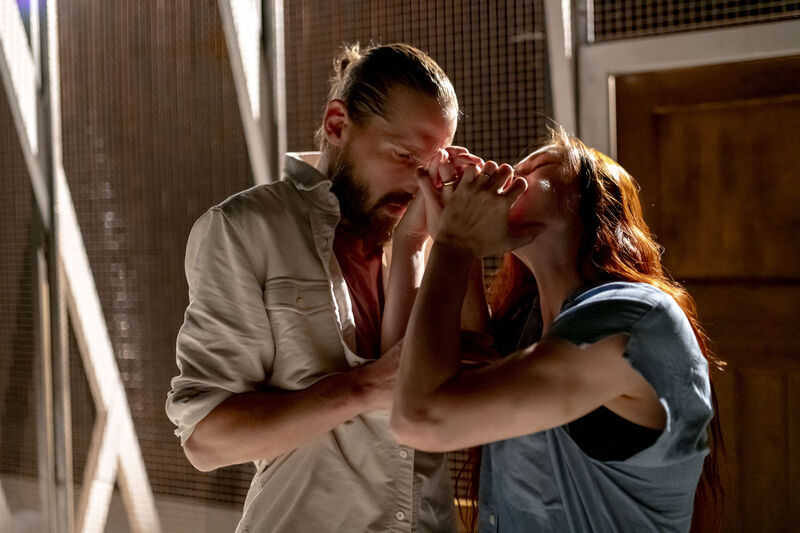 A man and woman stand next to each other with their arms entangled in an intimate moment