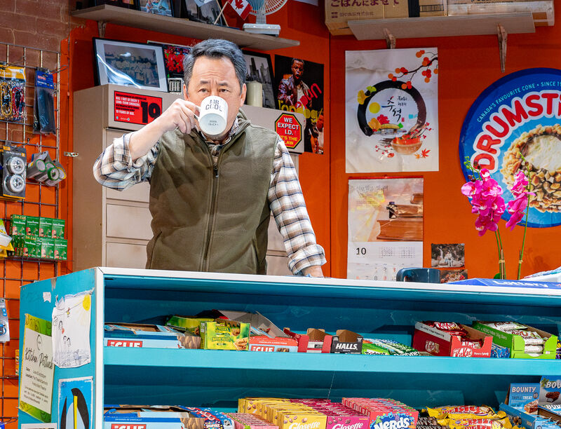 A man stood behind a counter holding a mug