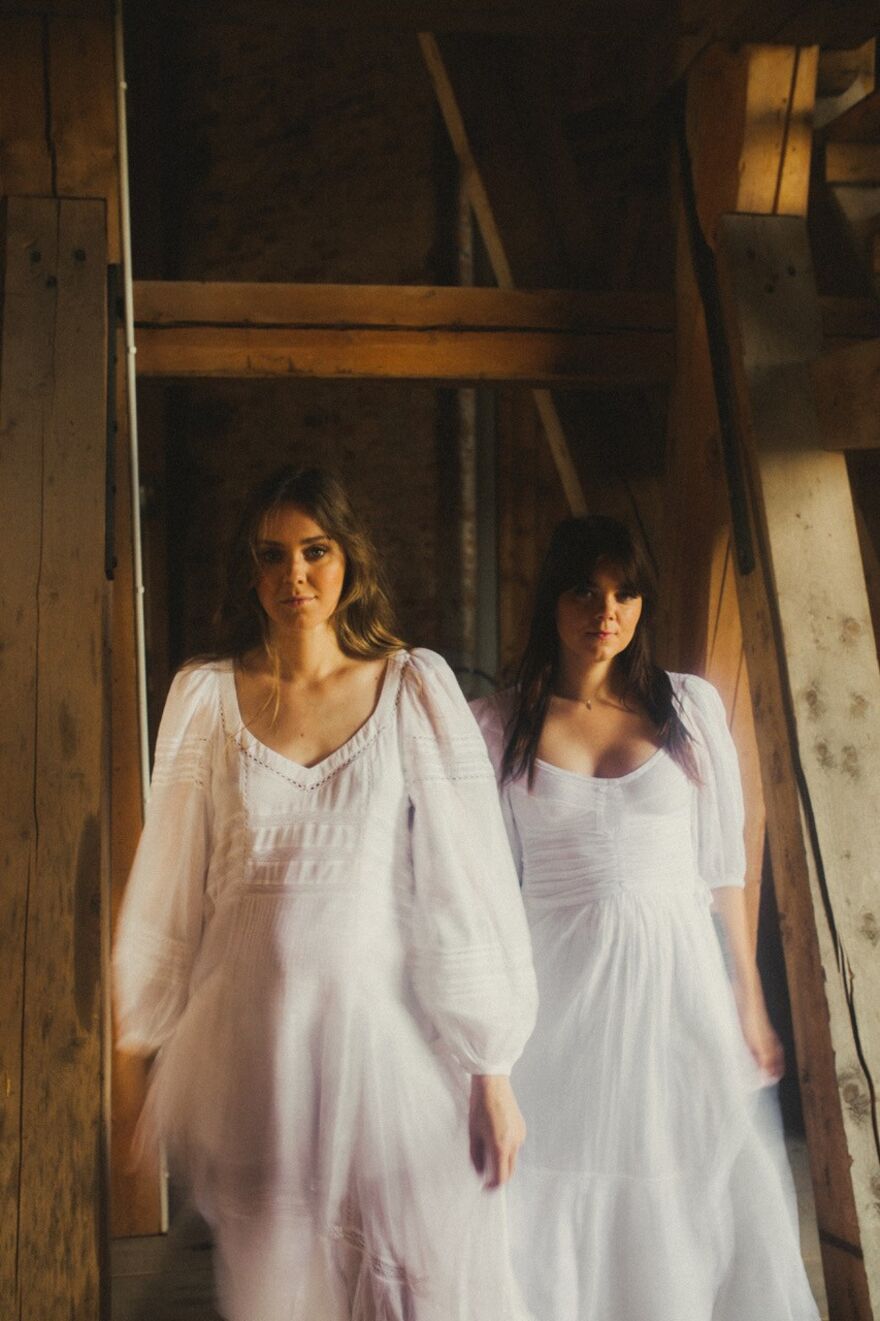 Two woman in white dresses standing in a wooden building