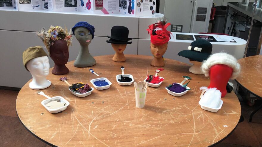 A table holds a variety of wig heads with different hats
