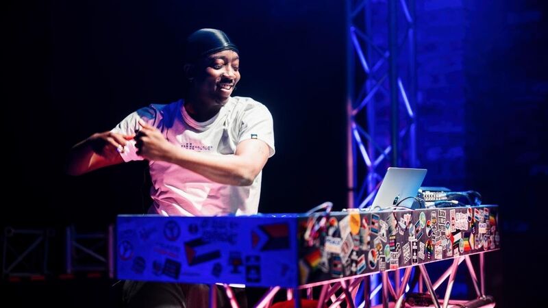 A dj stood behind his decks with a broad grin on his face