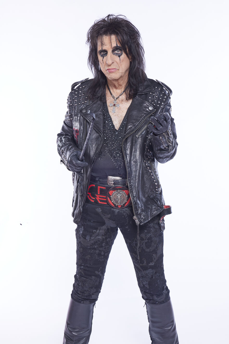 Alice Cooper wearing an all black outfit with black eye makeup against a white background