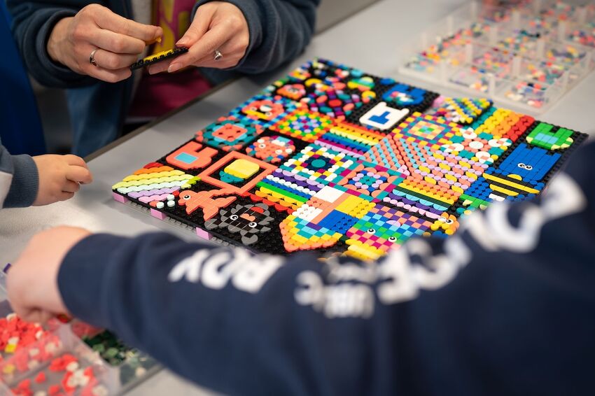 People are working together to create a quilt-like structure out of LEGO bricks