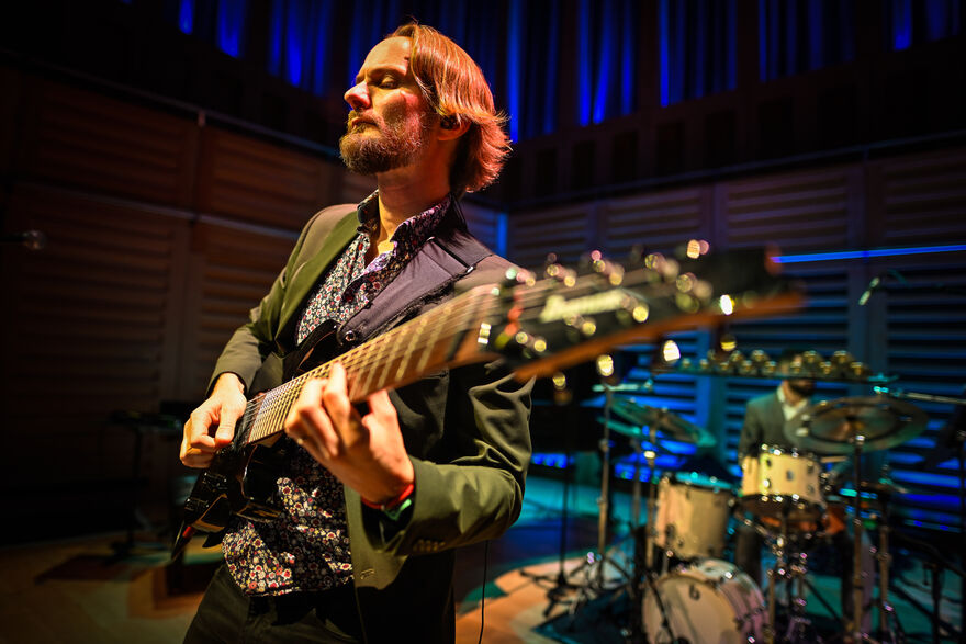 Ant Law playng the guitar in a dimly lit studio