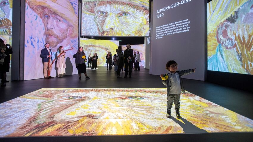 A child inside Van Gogh Alive pointing at some art on the wall