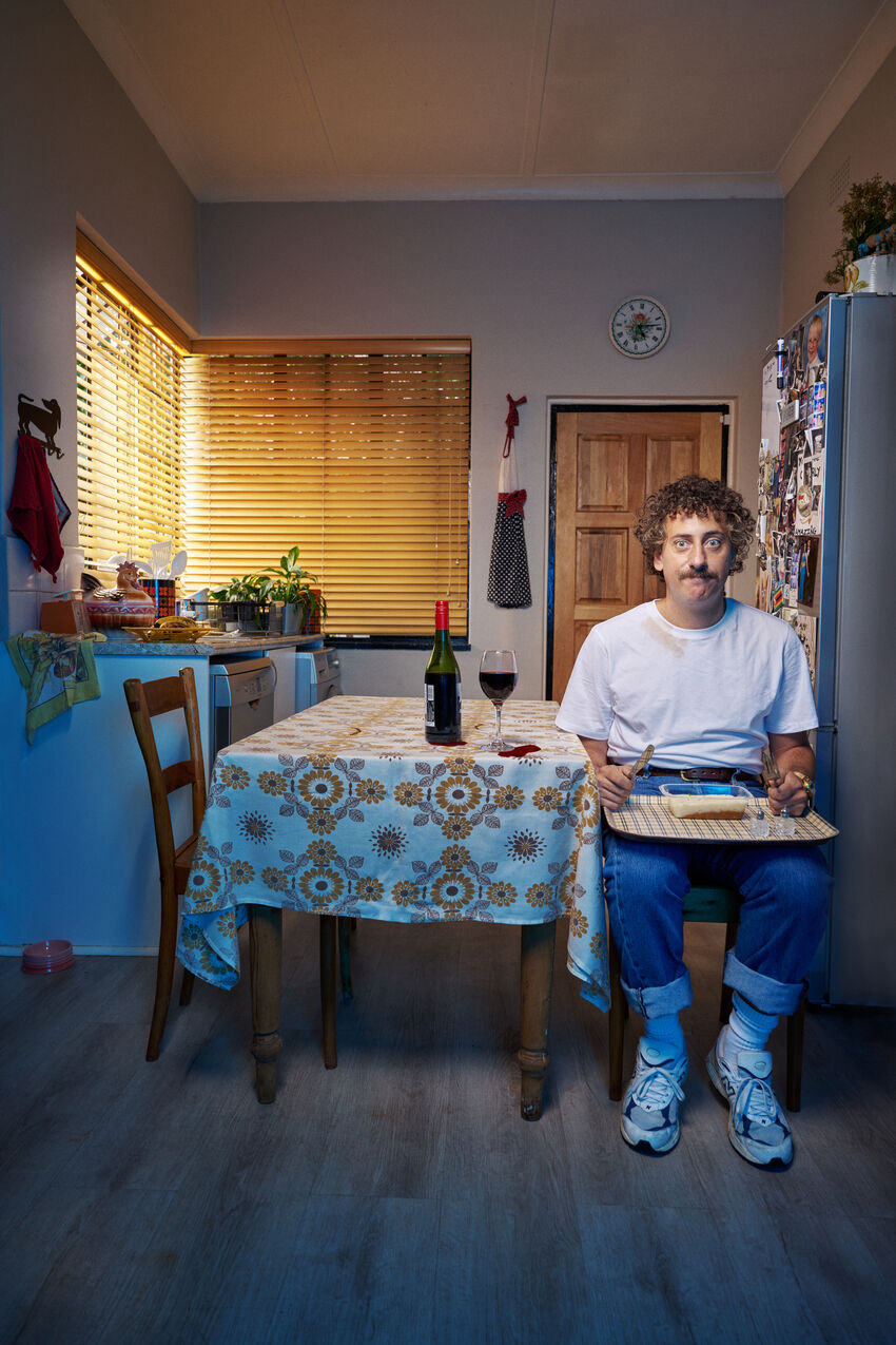 Schalk Bezuidenhout sitting at a table with a glass of red wine