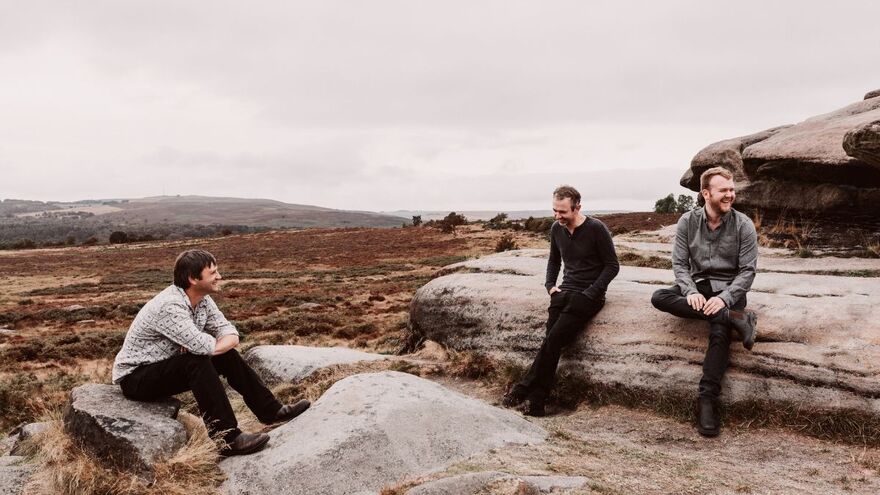 Three men sitting on large rocks on a British hillside