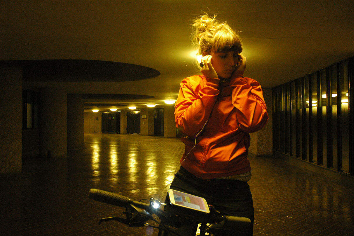 A woman on a bike listens to headphone