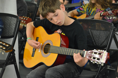 A young boy plays an acoustic guitar
