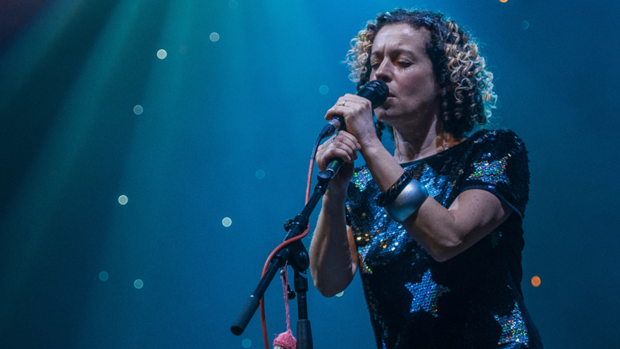 A person singing into a mic with a spotlight over them