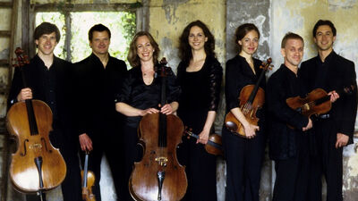The Aronowitz Ensemble face the camera holding their instruments, formally dressed in black
