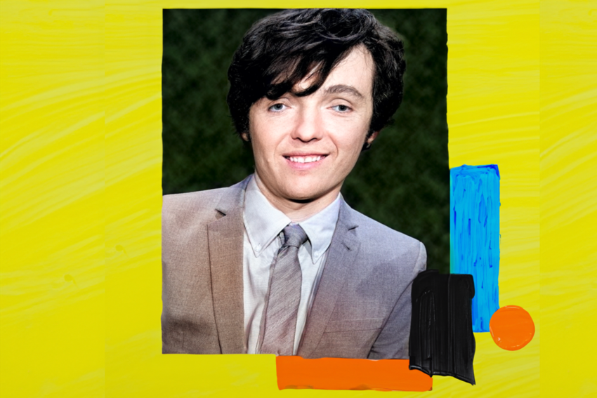 A white man with short black hair wearing a grey suit and tie