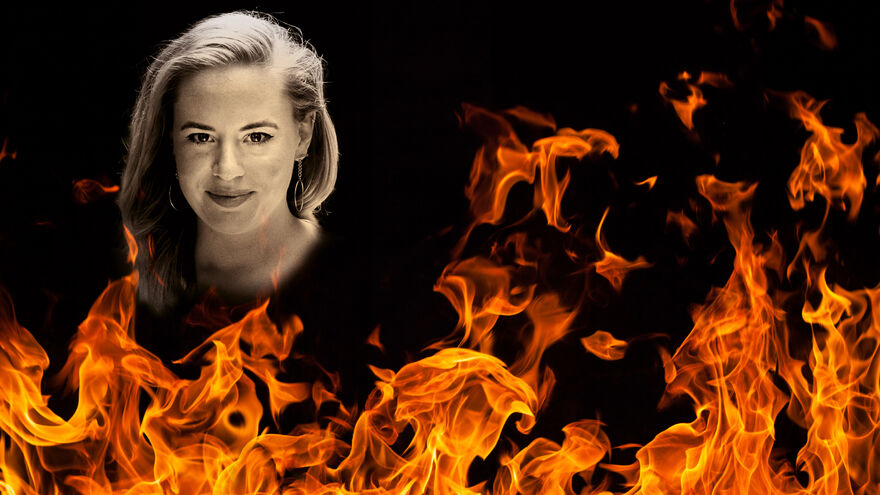 A white woman with long blonde hair is positioned behind lots of flames